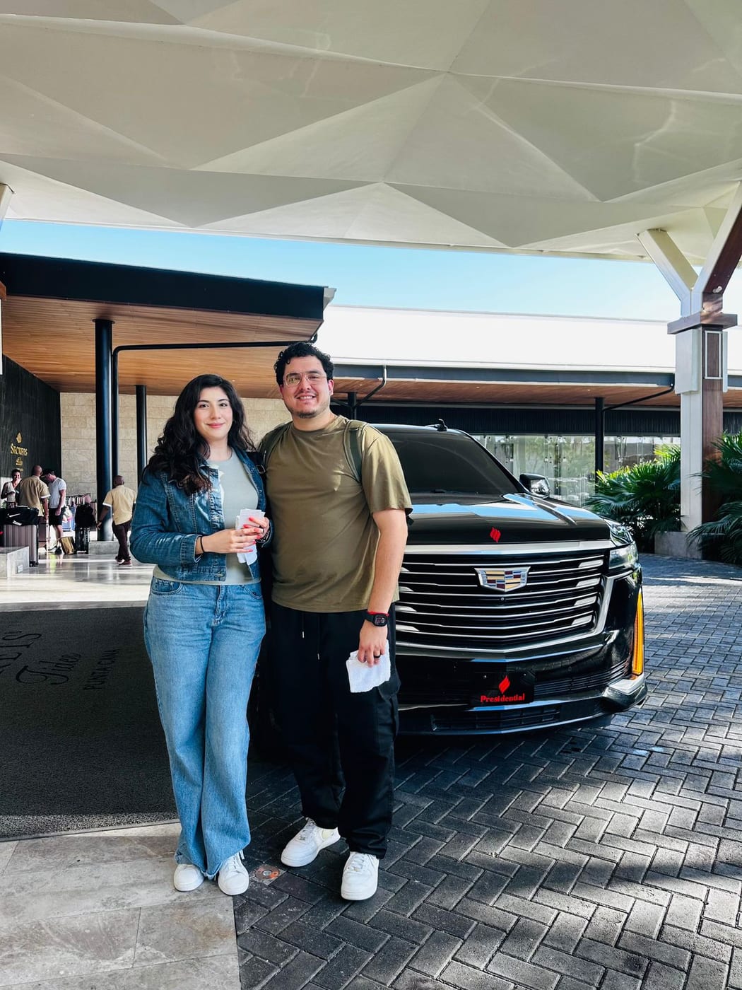 Couple beside a black Cadillac Escalade at a resort entrance