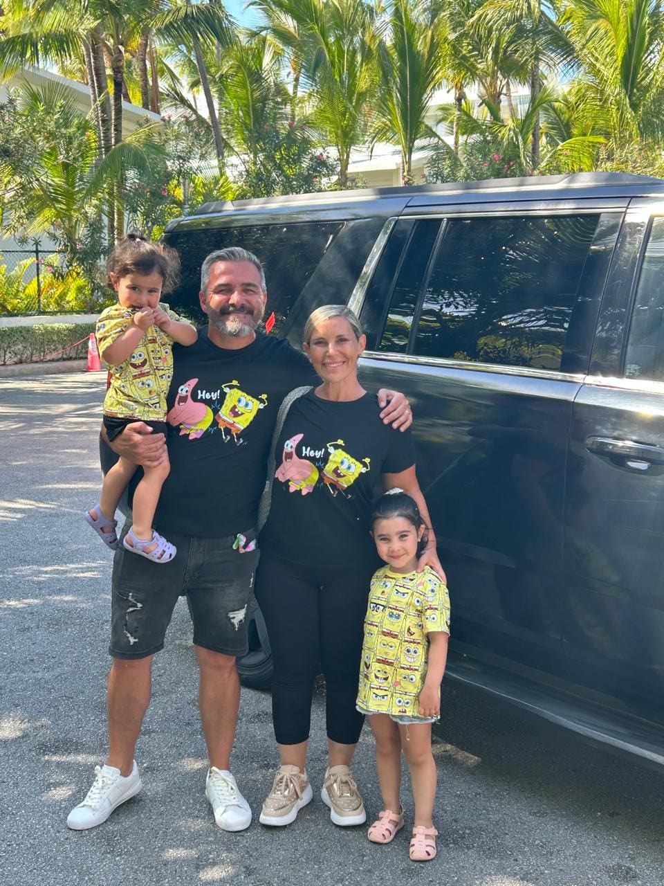 Family beside a black Suburban at a resort entrance