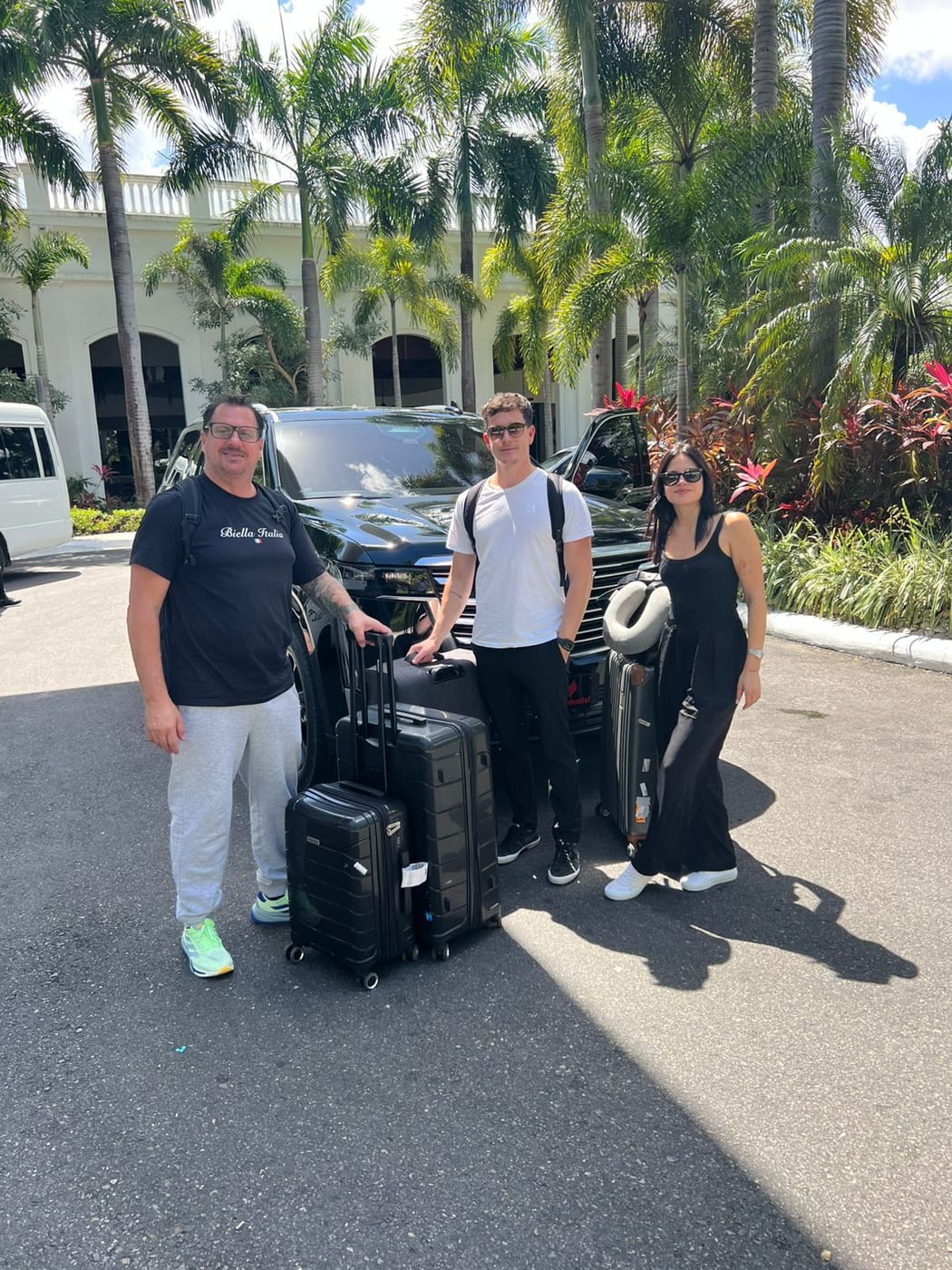 Guests with their luggage beside a black SUV at a hotel entrance